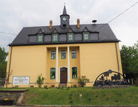 alte Schule in Thierfeld, gelbes Haus an einer Straße mit Turmuhr