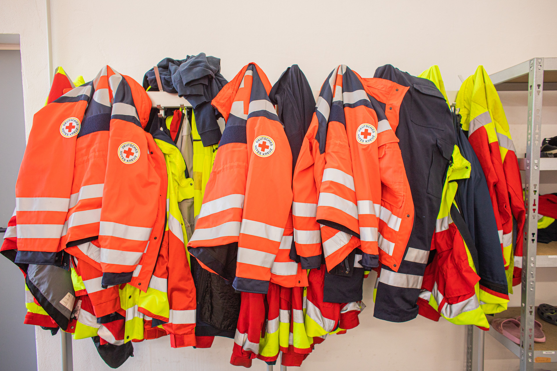 viele Einsatzjacken hängen an einer Garderobe an der Wand